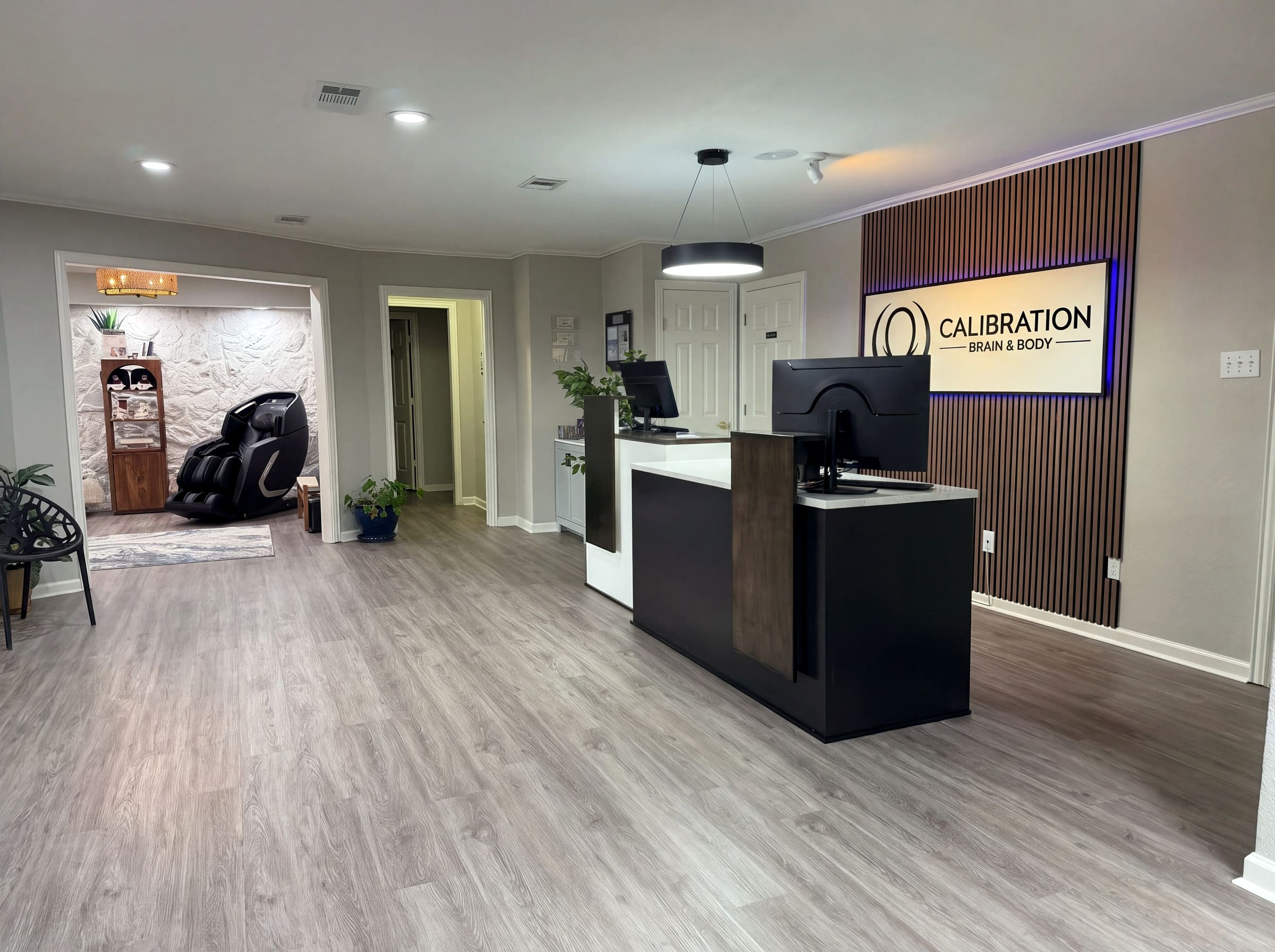 Calibration Brain & Body reception area in Frisco, Texas with the custom front desk, backlit logo wall, and wood slat feature panel